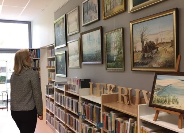 Kobieta ogląda wystawę malarstwa w bibliotece