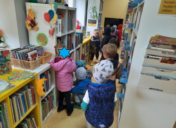 Dzieci przeglądają książki, stoją między regałami