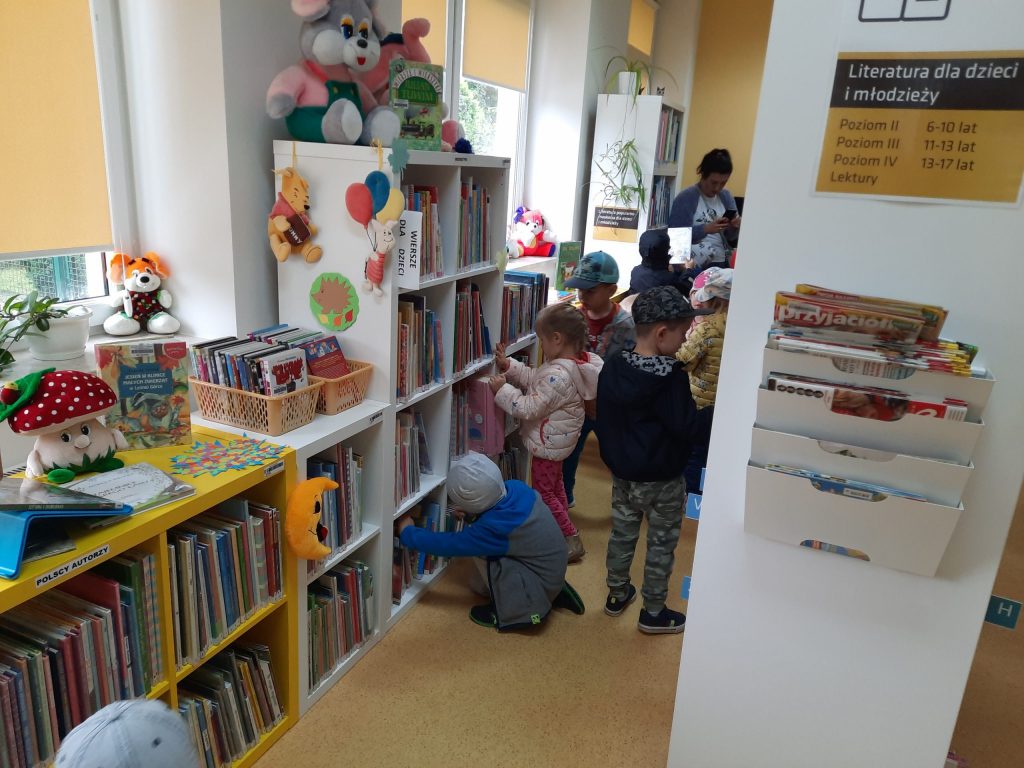 Dzieci przeglądają książki, stoją między regałami