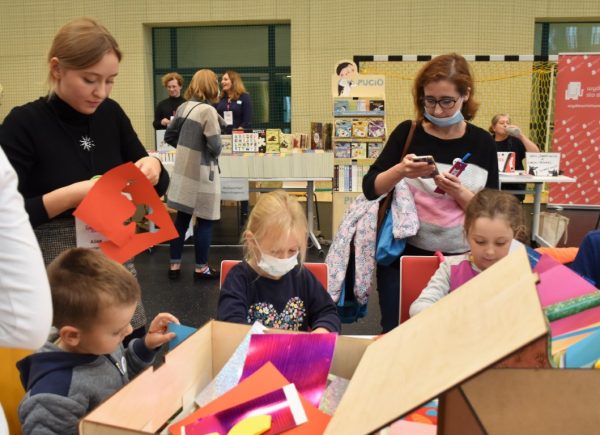 Dzieci tworzą własne książki przestrzenne. Wolontariuszka pomaga im.
