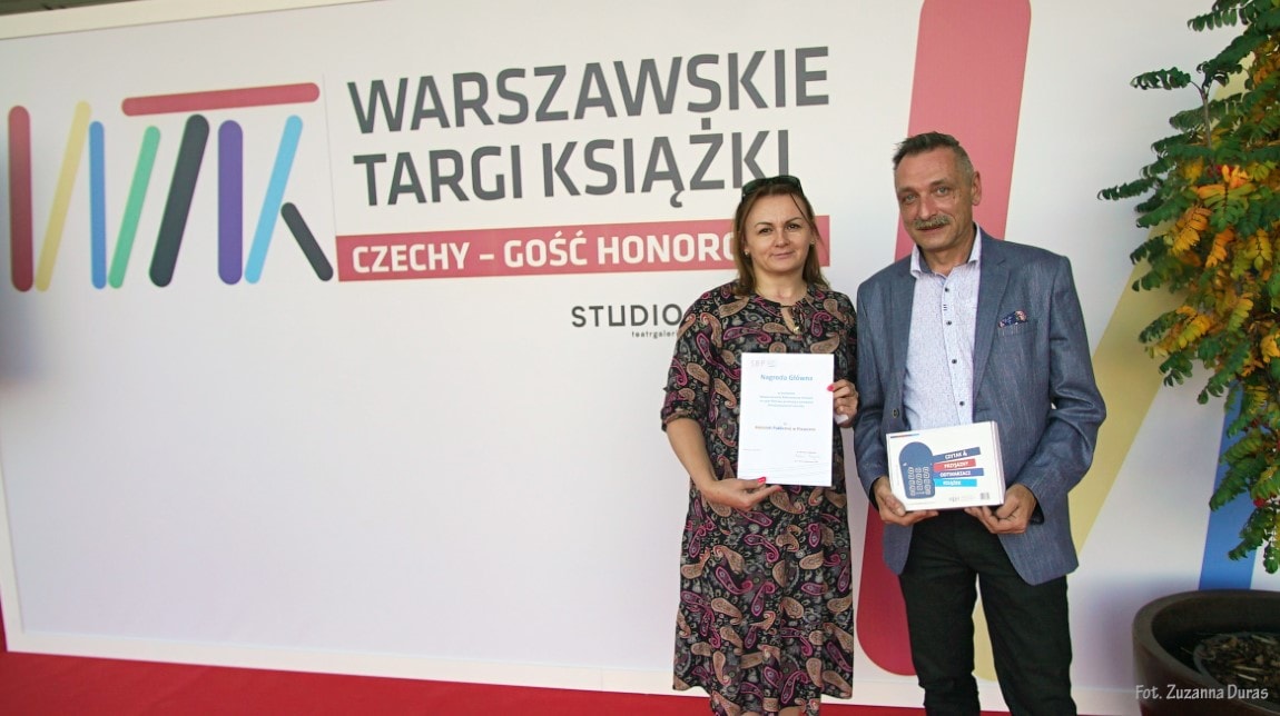 Zdjęcie przedstawia pracowników biblioteki - Agnieszkę Żelechowicz i Eligiusza Krok. Kobieta trzyma w rękach dyplom, a mężczyzna czytak. Pozują do zdjęcia.