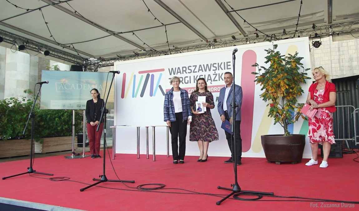Zdjęcie przedstawia pracowników biblioteki - Agnieszkę Żelechowicz i Eligiusza Krok wraz z jurorką konkursu na spot #NieZostawiamCzytelnika. Stoją oni na scenie i pozują do zdjęcia.