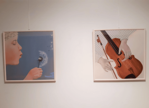 Zdjęcie przedstawia ilustracje z wystawy "Abecadło" - dziecko z dmuchawcem i ręce trzymające skrzypce.