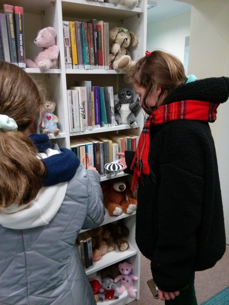 Dziewczynki poszukują rysunków dyń w bibliotece