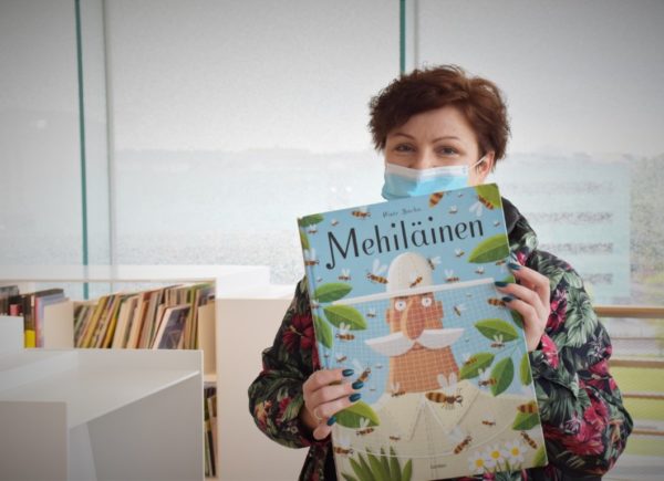 Na zdjęciu widać uczestniczkę projektu PO WER. Trzyma ona w ręku fińskie wydanie książki "Pszczoły" Piotra Sochy.