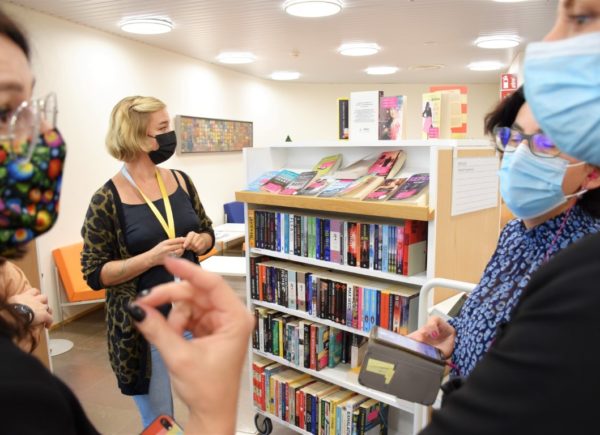 Na zdjęciu widać przewodniczkę po bibliotece w Töölö. Kobieta stoi przy regałach na książki.