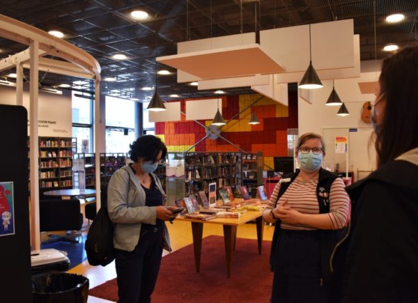 Zdjęcie przedstawia uczestniczkę projektu PO WER i przewodniczkę. Kobiety stoją, za nimi znajdują się regały z książkami.