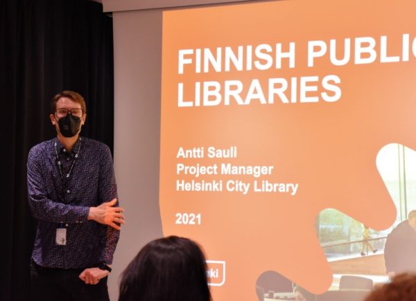 Zdjęcie ukazuje pracownika biblioteki w Oodi. Mężczyzna przedstawia prezentacje multimedialną.