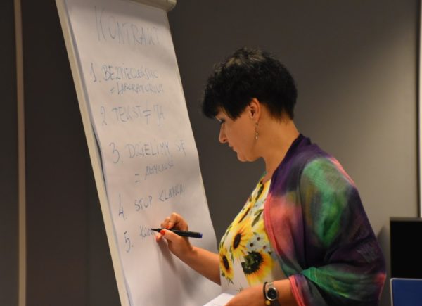 Agnieszka Lis pisze na tablicy reguły dotyczące warsztatów