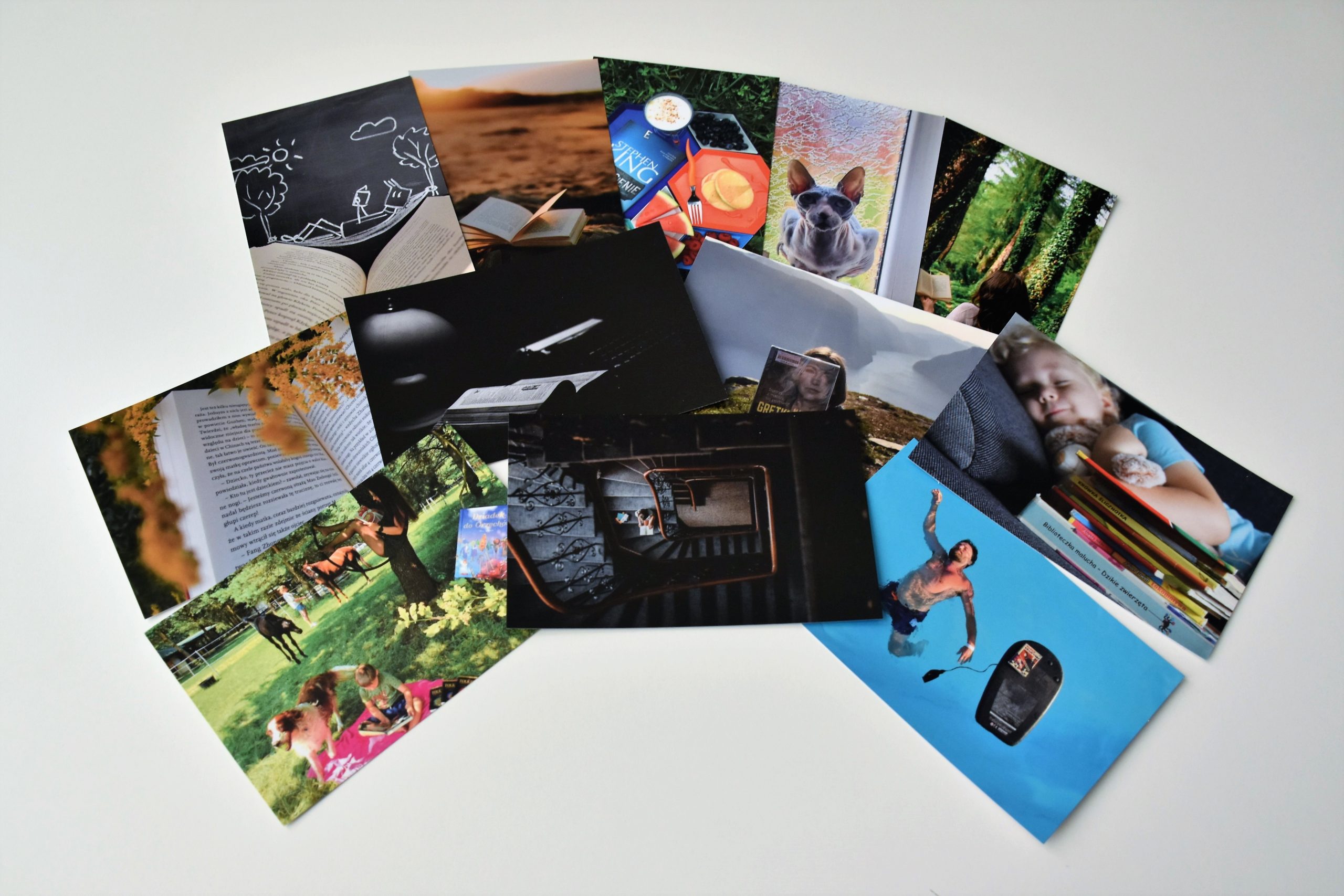 Zdjęcie przedstawia pocztówki z nagrodzonymi i wyróżnionymi fotografiami w konkursie "Wakacje z książką 2021".