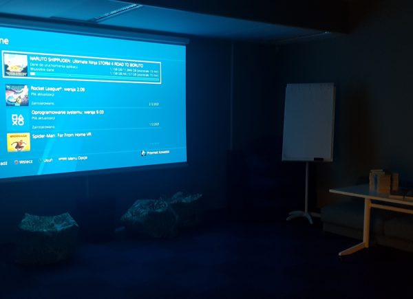 Ekran w sali kinowej z instalującą się grą
