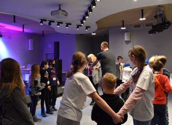 Studenci trzymają się za ręce i biorą udział w grze przygotowanej przez animatora Michała Przybyłowicza.