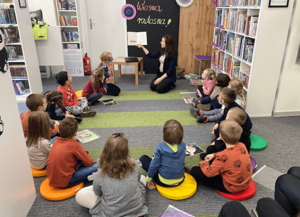 Dzieci słuchają tekstu czytanego przez bibliotekarza
