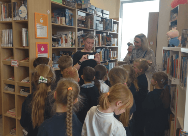 Bibliotekarka pokazuje dzieciom kartę biblioteczną