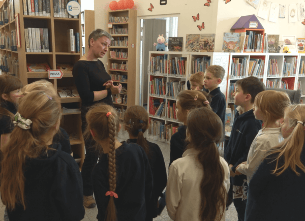 Bibliotekarka objaśnia dzieciom zasady wypożyczania książek