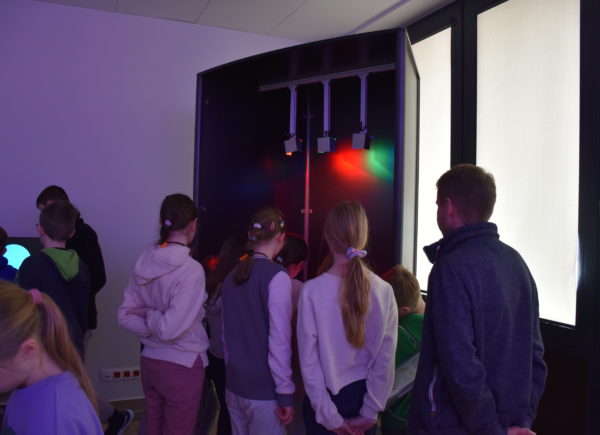 Dzieci eksperymentują z barwami światła przy eksponacie z przestrzeni SOWA