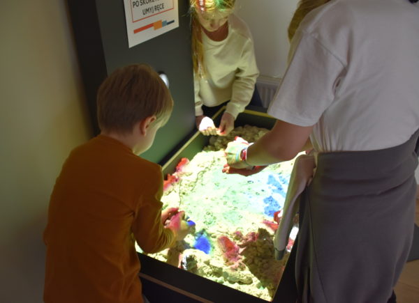 Studenci korzystają z piasku kinetycznego w eksponacie "Usyp mapę"
