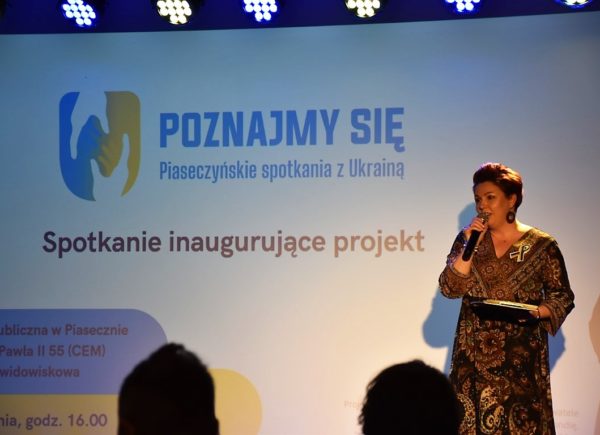 Zastępca dyrektora biblioteki Sylwia Chojnacka-Tuzimek na scenie z mikrofonem.