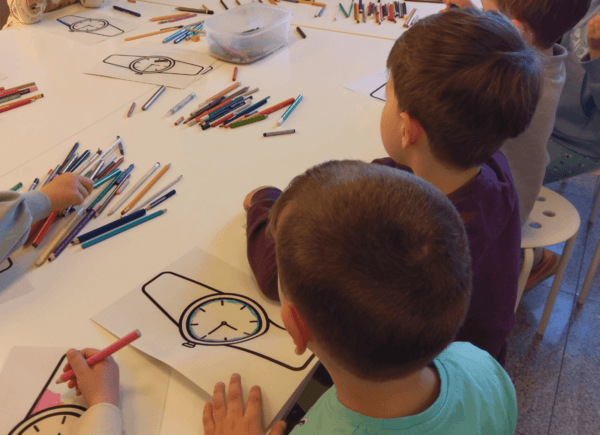 Dzieci kolorują kolorowanki przedstawiające zegarki
