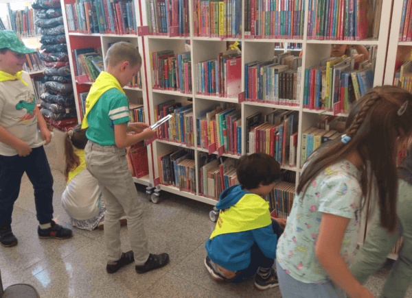 Dzieci szukają papierowych zegarków ukrytych pośród książek