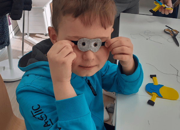 Chłopiec trzyma uszyte oczy dla swojej figurki