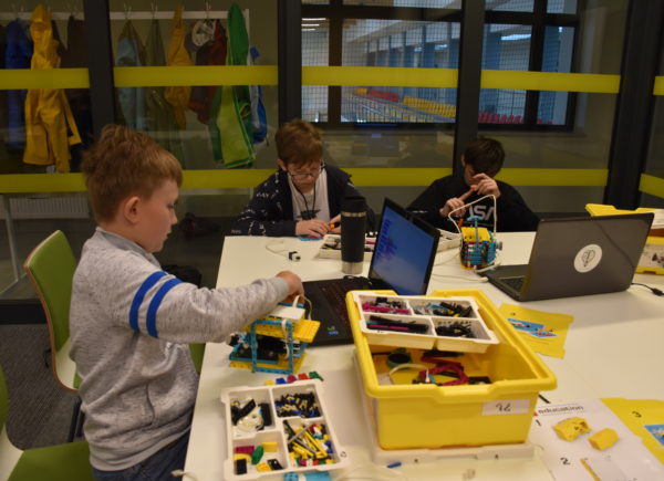 Trzech chłopców buduje z kolorowych klocków LEGO