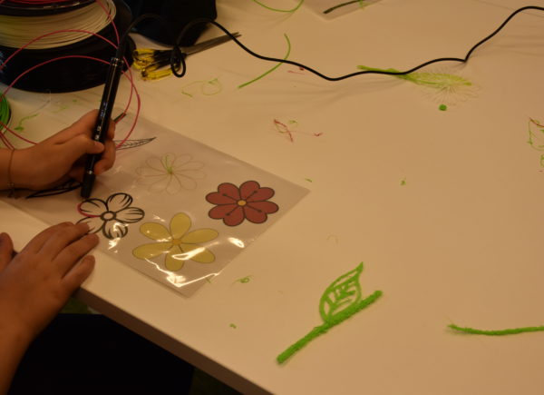 Uczestnik warsztatów wykonuje kwiatek z wykorzystaniem długopisu 3D