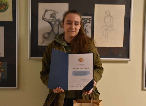 Paulina Nowak pozuje z dyplomem do zdjęcia.