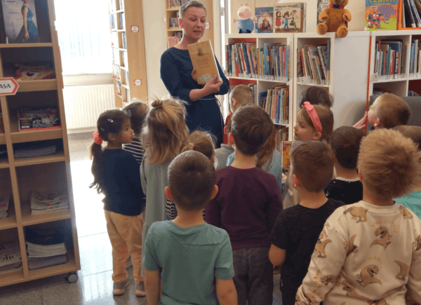 Bibliotekarka pokazuje dzieciom księgozbiór