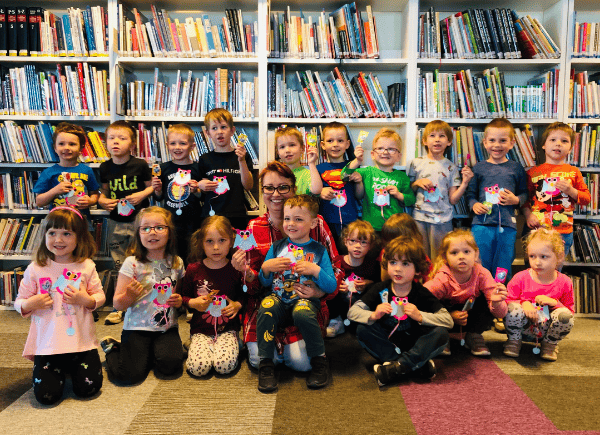 Dzieci prezentują wykonane podczas lekcji bibliotecznej zakładki sowy