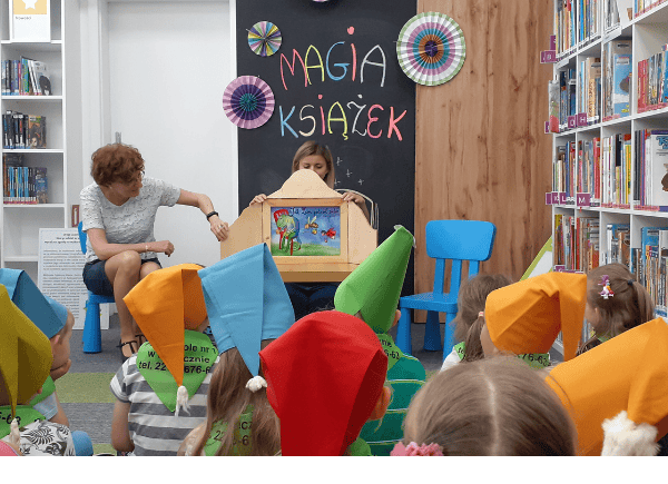 Dzieci słuchają bajki czytanej przez bibliotekarkę