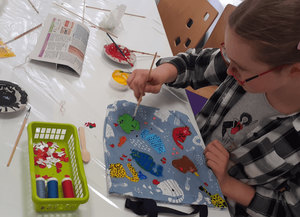 Dziewczynka malująca farbami torbę