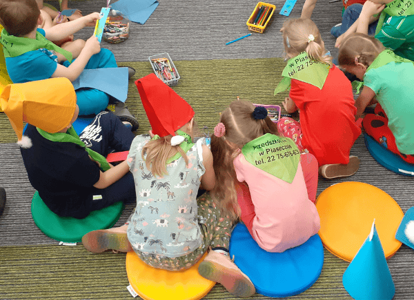 Tworzenie zakładek przez dzieci siedzące na dywanie