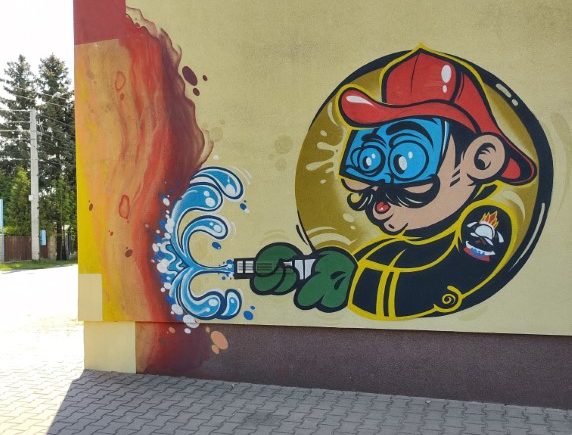Graffiti przedstawiające strażaka na ścianie budynku OSP.