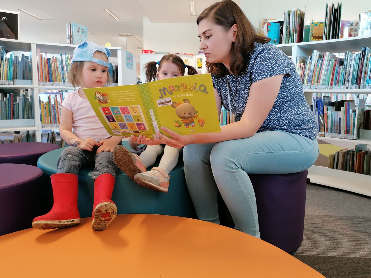 Bibliotekarka czyta dzieciom książeczkę o przygodach Marysi
