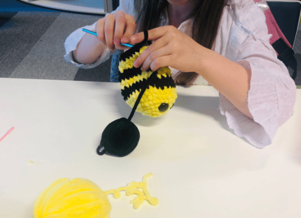 Dziewczynka robi na szydełku maskotkę - pszczółkę
