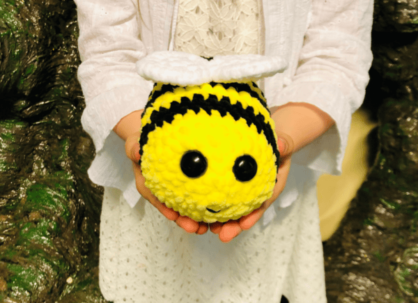 Dziewczynka prezentuje wykonaną na szydełku pszczółkę
