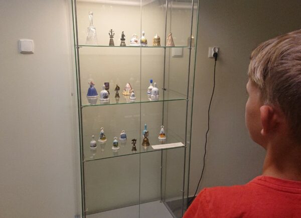 Chłopiec ogląda wystawę dzwonków umiezczoną w gablocie