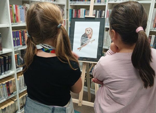 Dziewczynki podziwiają ilustracje z wystawy