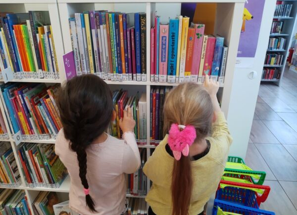 Dziewczyki przeglądają książki na półkach