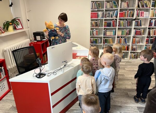 Dzieci oglądają maskotkę biblioteki