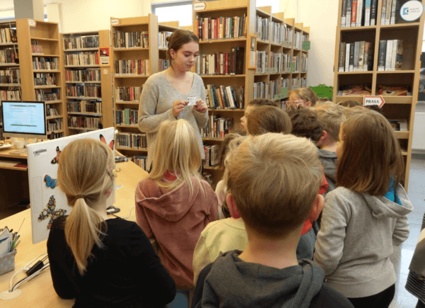 Bibliotekarka pokazuje dzieciom kartę biblioteczną