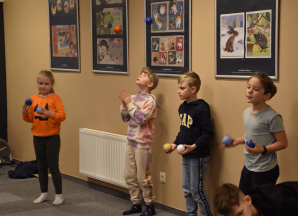Grupa dzieci podrzuca kolorowe piłeczki ćwicząc żonglowanie