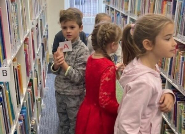 Dzieci szukają liter ukrytych między książkami