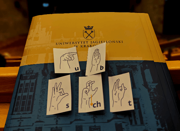 Teczka Uniwersytetu Jagiellońskiego, na której są naklejone karteczki z literami w języku migowym.