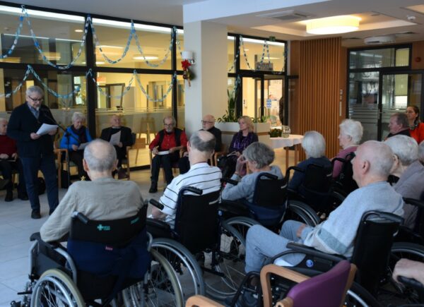 Seniorzy słuchający poezji, prozy i melodii kolęd granych na wiolonczeli
