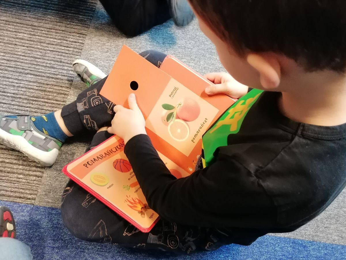 Przedszkolak ogląda książeczkę zapachową