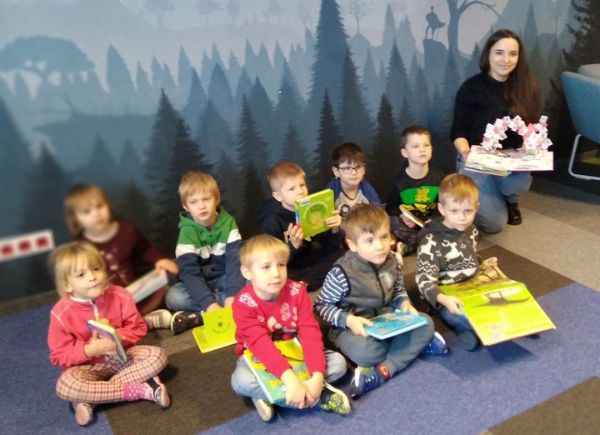 Przedszkolaki wraz z Panią Bibliotekarką pozują do wspólnego zdjęcia. Dzieci trzymają w rączkach biblioteczne książeczki.