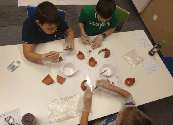 Dzieci sklejają fragmenty potłuczonej gliny