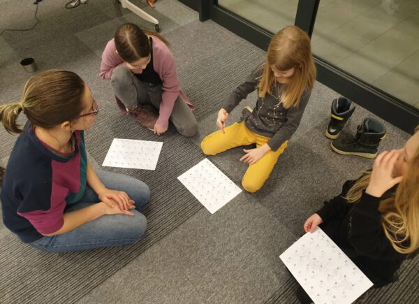 Dzieci siedzące na podłodze i uczące się języka migowego